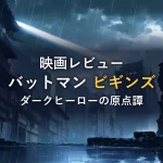 雨のゴシック調の街並みに差し込むサーチライトと石像のシルエットのイメージ（映画『バットマン ビギンズ』の感想記事のイメージカット）